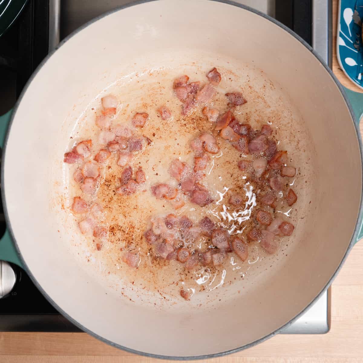 diced bacon being fried in a soup pot. 
