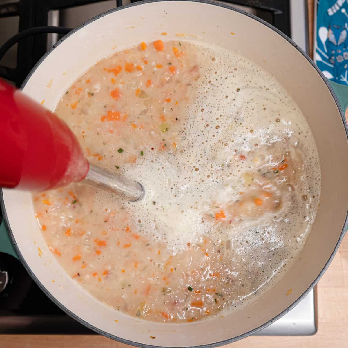 soup ingredients being partially pureed with a hand blender. 