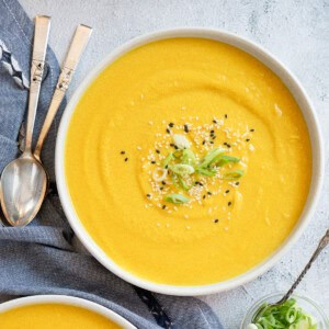 one bowl of miso butternut squash soup garnished with sliced green onions and black and white sesame seeds.