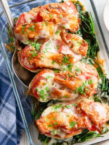 Chicken club bake in a casserole dish with a serving spoon and a blue towel in the background.