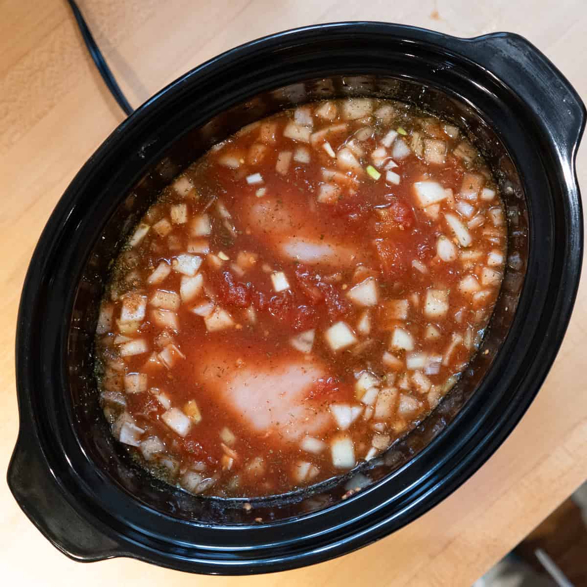 Raw ingredients inside a slow cooker ready to be cooked.
