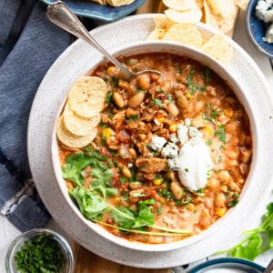 Buffalo chicken chili in a bowl topped with sour cream and blue cheese, ready to be served.