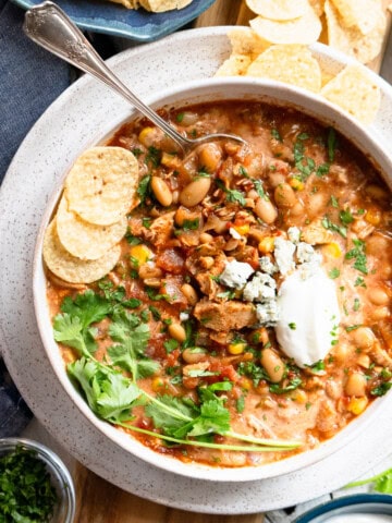 Buffalo chicken chili in a bowl topped with sour cream and blue cheese, ready to be served.