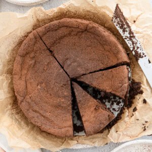 Chocolate souffle cake dusted with cocoa powder with 2 slices cut into it.