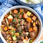 Slow cooker beef and Guinness stew in a serving dish with a bowl of potato turnip mash on the side.