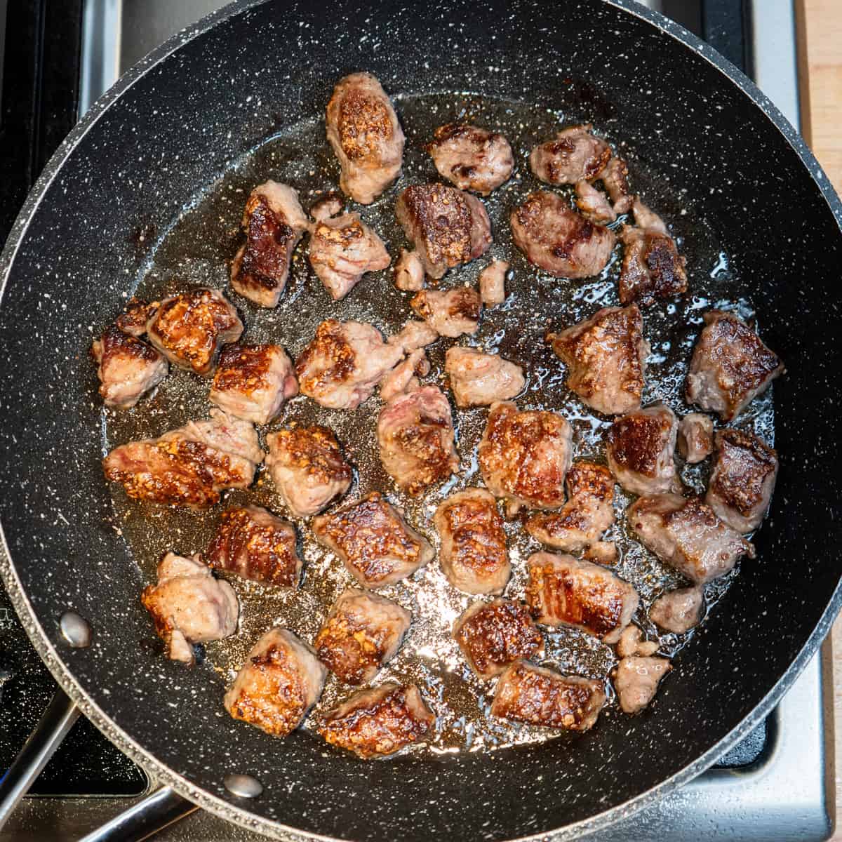Cubes of beef browning in a skillet.