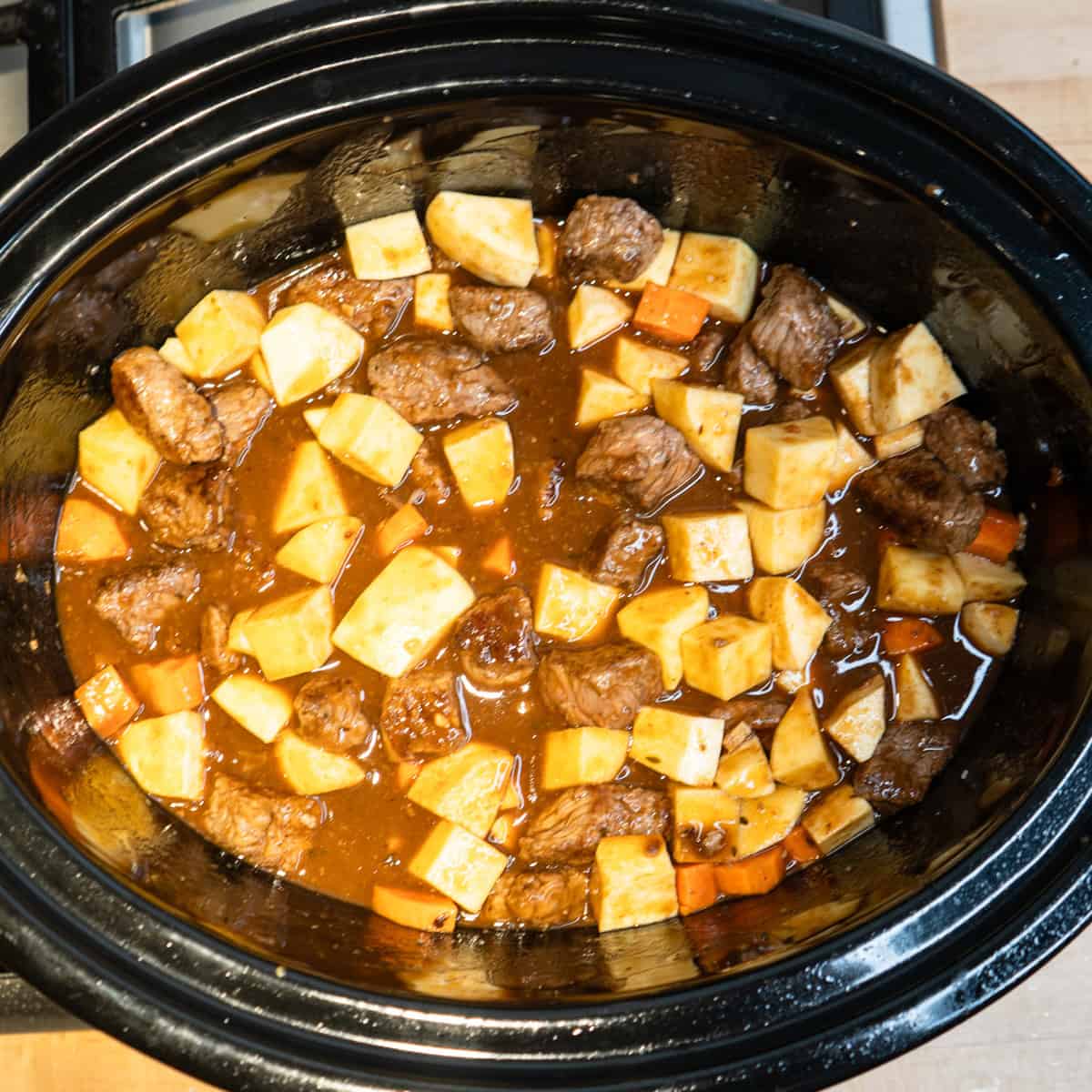 Beef, vegetables and gravy in a slow cooker.