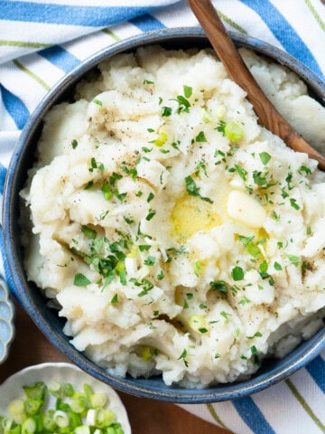 Potato turnip mash in a serving dish with a wooden spoon.