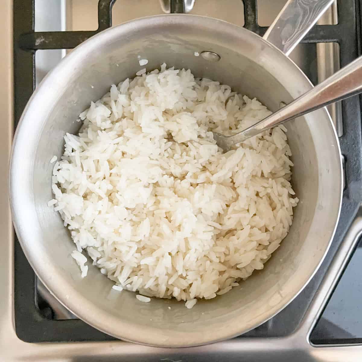Finished coconut jasmine rice in the pot with a fork for fluffing.