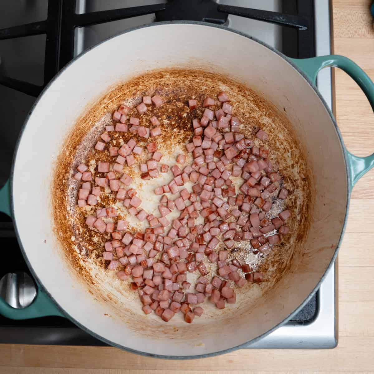 Cubes of ham browning in a pot.