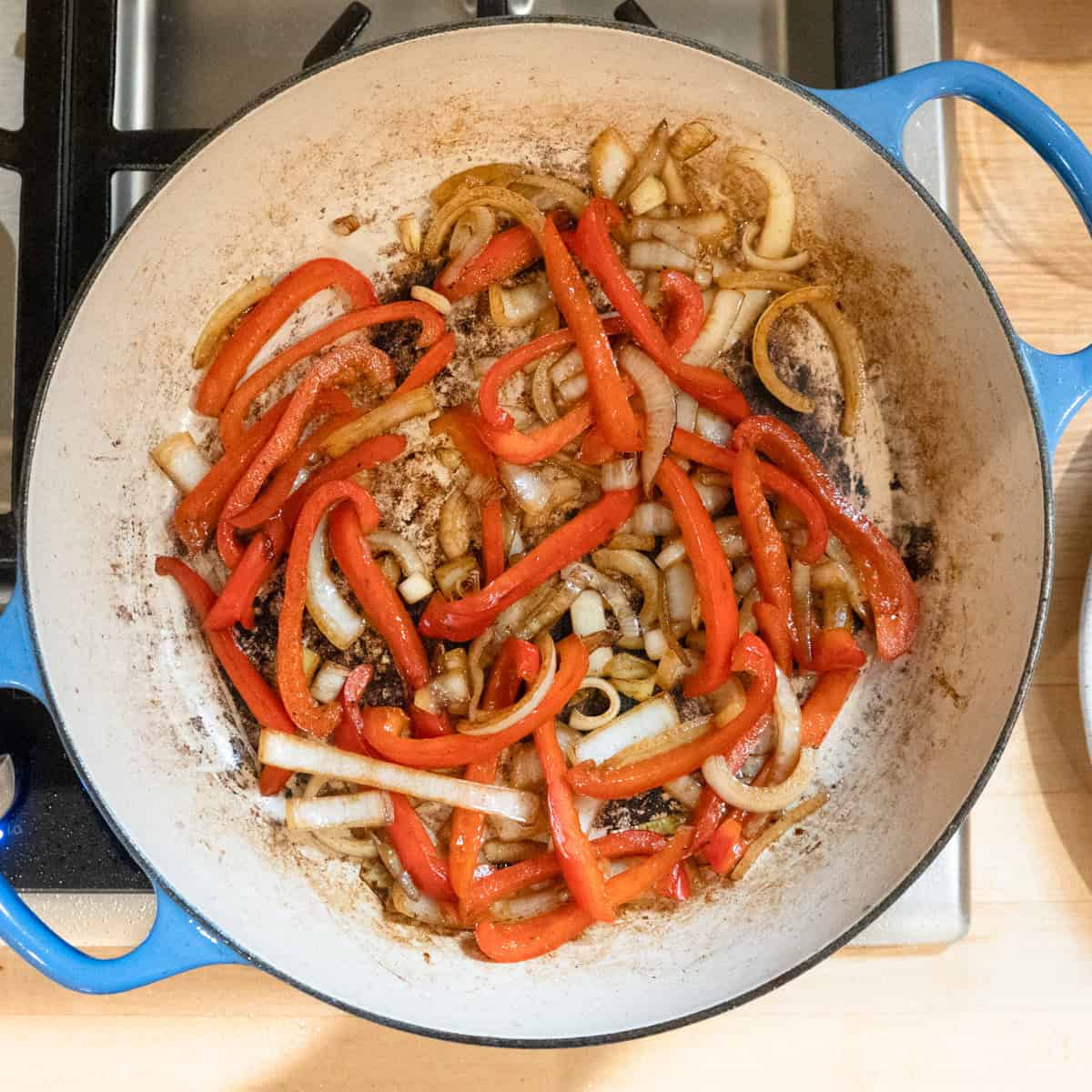 Onions and red pepper frying in a skillet.