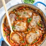 Boneless pork chops in a sweet and sour pineapple sauce with a wooden serving spoon.