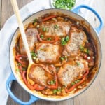 Boneless pork chops in a sweet and sour pineapple sauce with a wooden serving spoon.