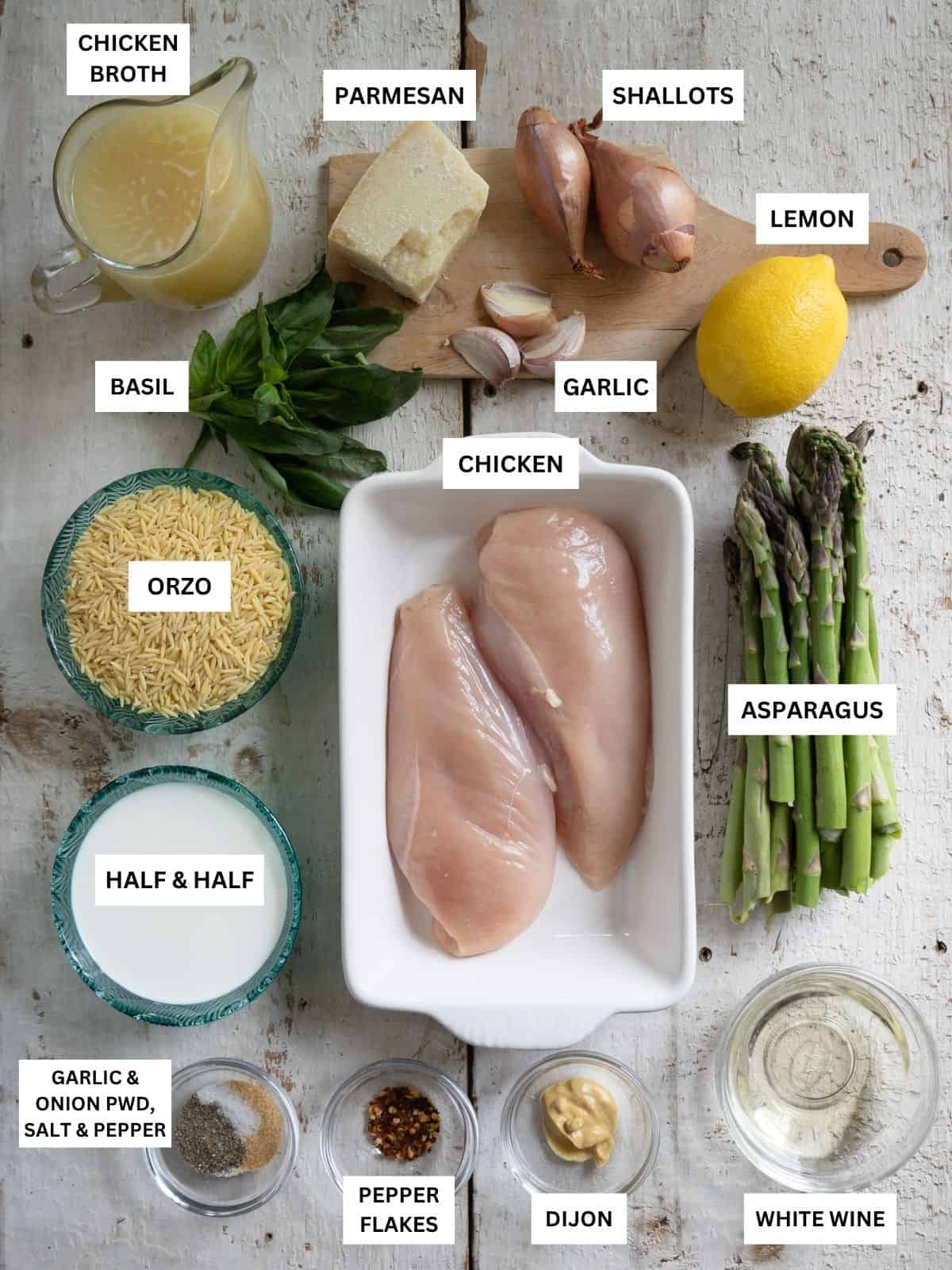 All ingredients needed to make chicken and asparagus in orzo labeled and laid out on a board.