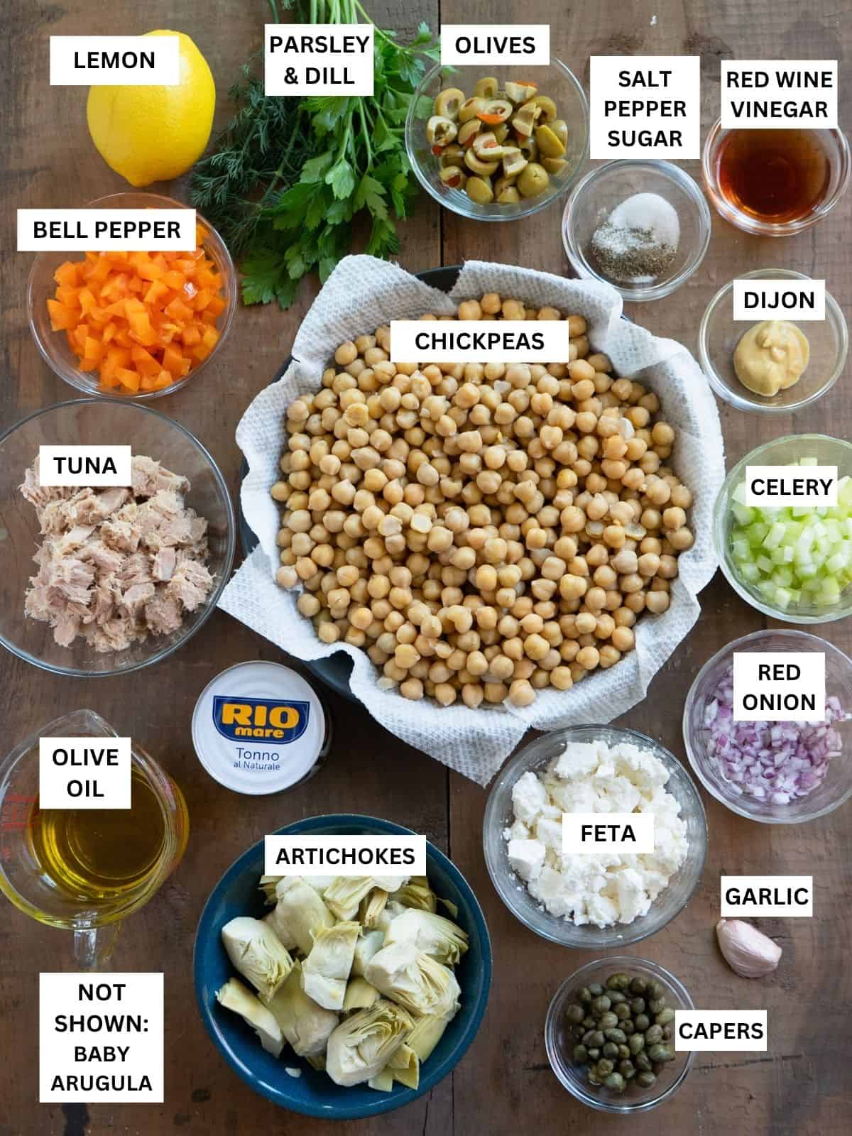 All ingredients to make chickpea tuna salad, prepared and labeled on a wood board.