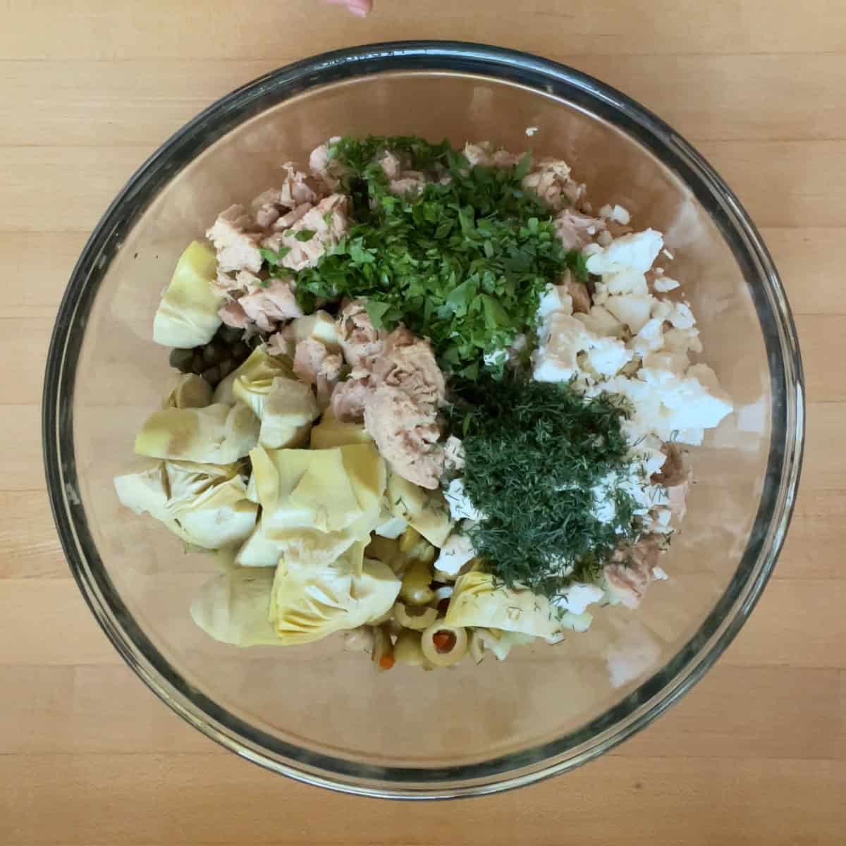 All ingredients to make chickpea and tuna salad in a bowl before being mixed with the dressing.