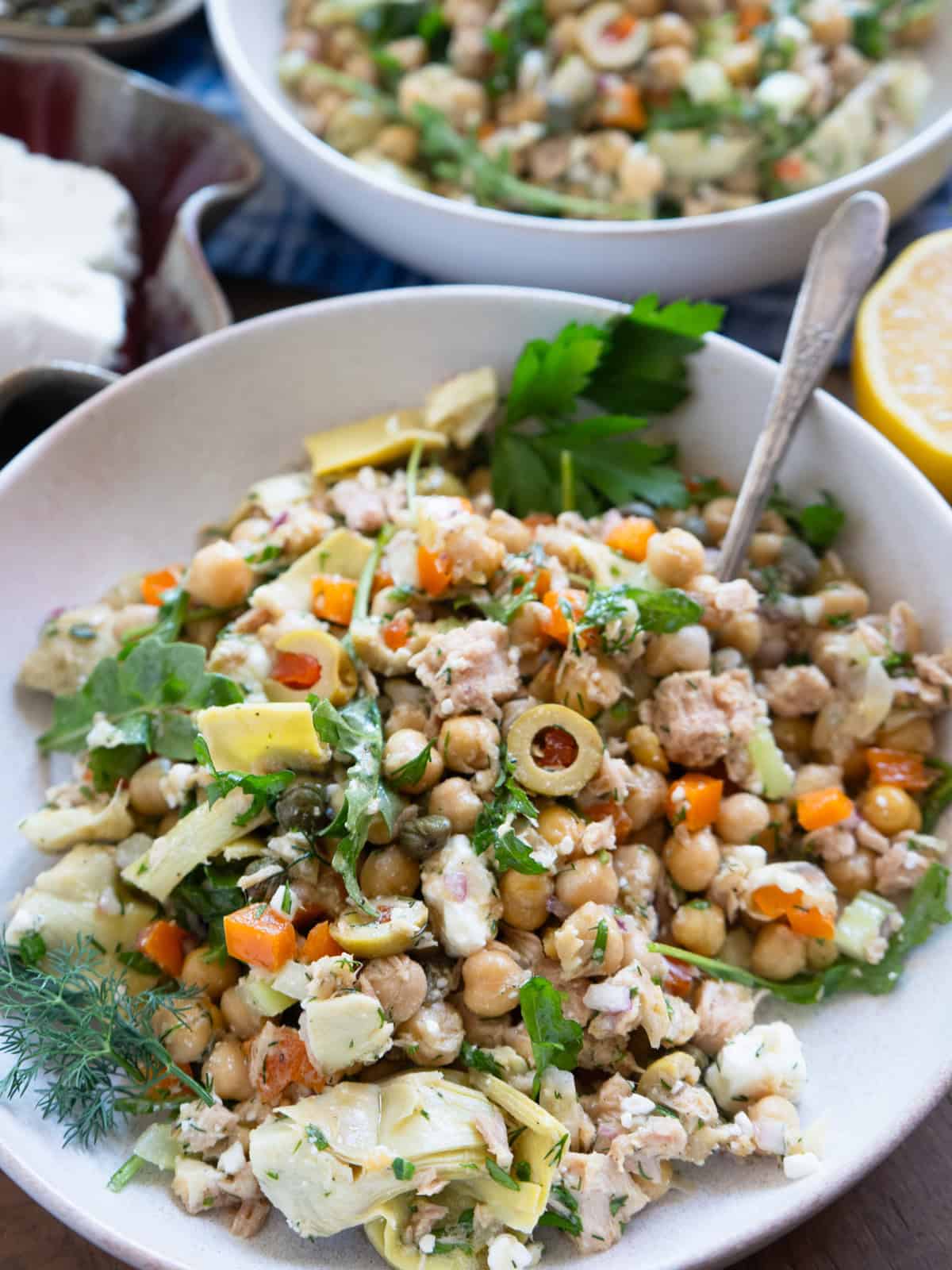 One serving of chickpea and tuna salad sitting on a blue towel with a fork ready to eat!