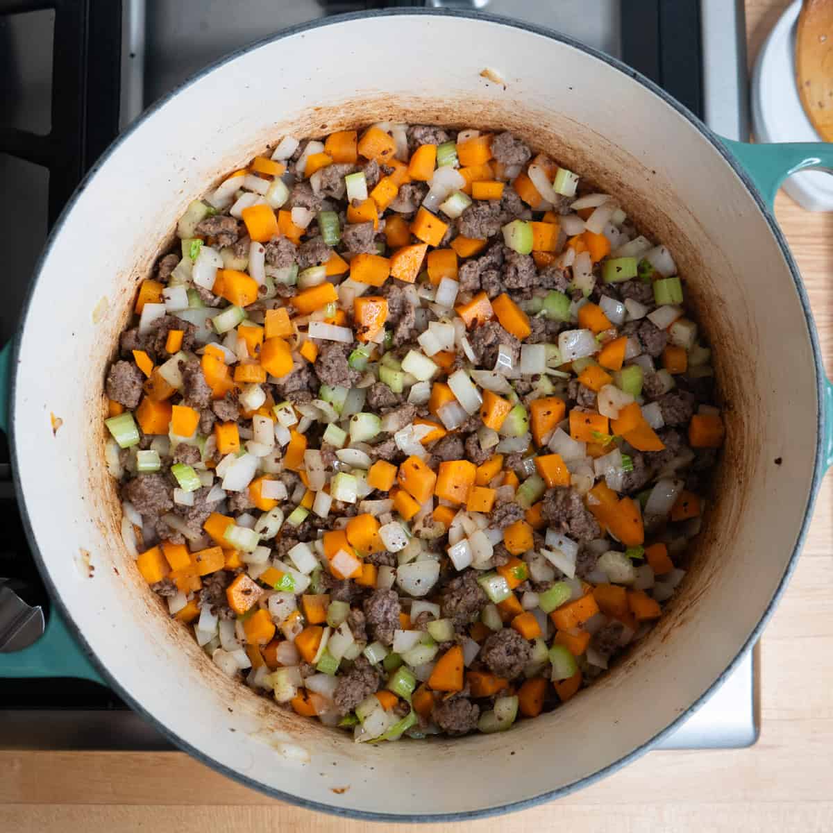 Ground beef and vegetables cooking in a large soup pot.