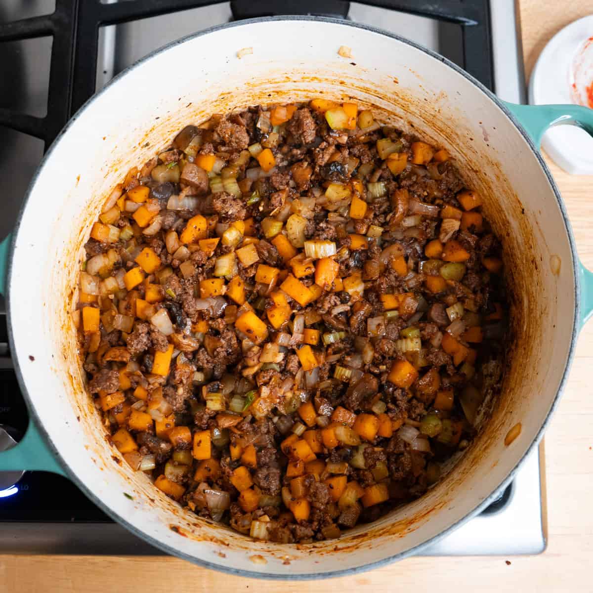 Ground beef, vegetables and tomato paste cooking in a large soup pot.
