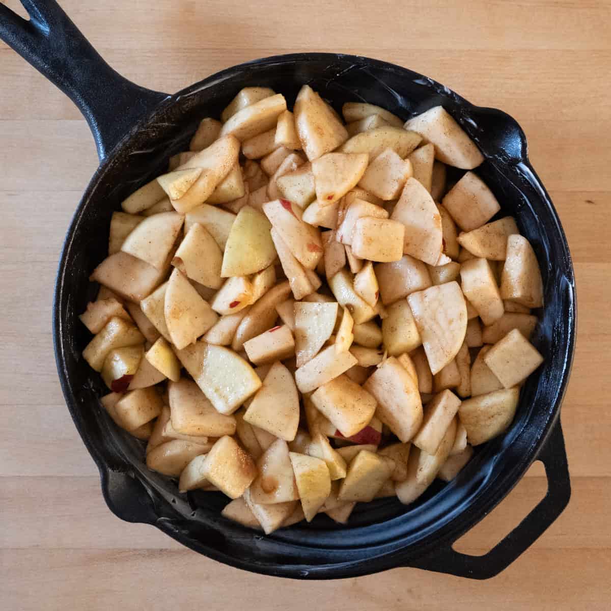 Prepared apples in a greased cast iron skillet.