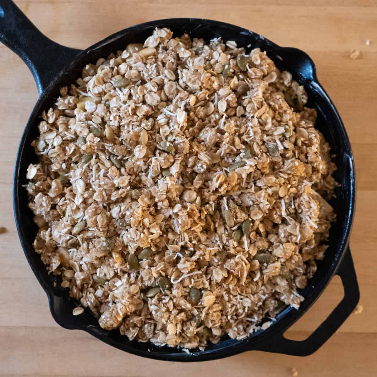 Apple crisp in a cast iron skillet with topping. Ready to go into the oven.